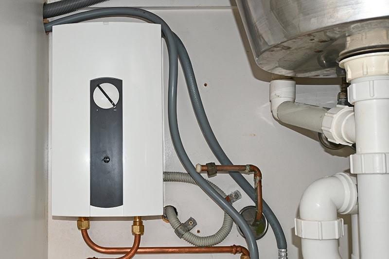 Continuous flow electric hot water heater under a sink.